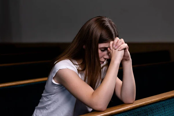 Una chica cristiana triste en camisa blanca está sentada y rezando con — Foto de Stock