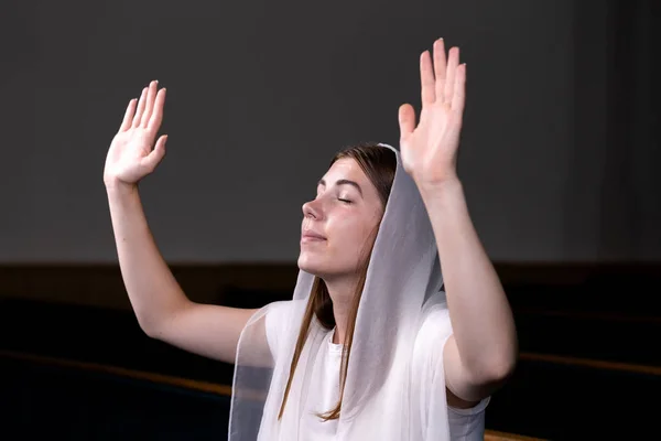 A young modest girl with a handkerchief on her head is sitting i