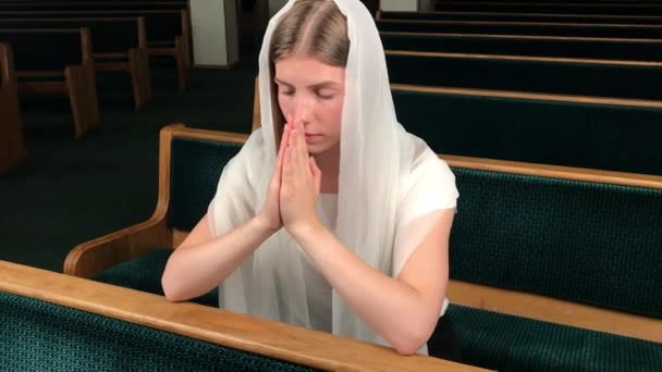 Joven religiosa devota orando en la iglesia bautista. Fiel católica en la catedral europea: dentro del lugar santo — Vídeos de Stock