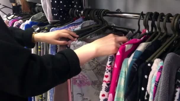 Vista de branco adolescente menina escolher roupas em uma loja de segunda mão . — Vídeo de Stock