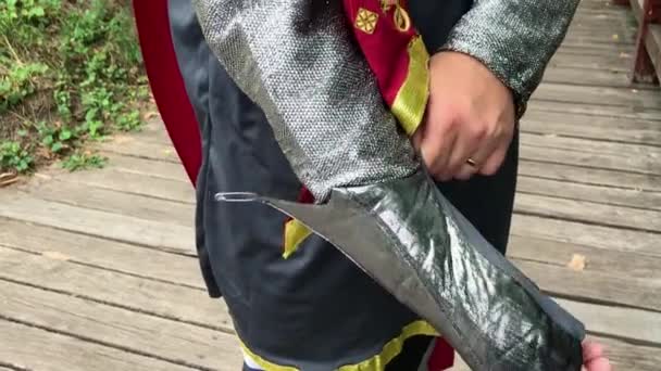 Ein junger bärtiger Kerl zieht einen Ritteranzug oder eine Ritterrüstung an. Zeitlupe Nahaufnahme — Stockvideo
