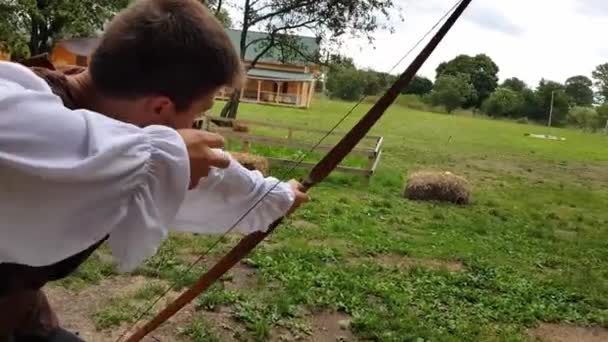 KOROSTEN - AGO, 12 de agosto de 2019: un joven con un disfraz medieval dispara un arco en un pajar — Vídeos de Stock