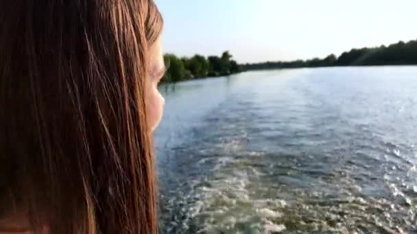 Retrato vista lateral jovem mulher caucasiana atraente fechando os olhos e virando o rosto para o sol apreciando os raios de sol e banhos de sol. Navegando em um barco de prazer no rio em um dia de verão — Vídeo de Stock