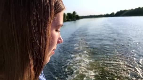 Retrato lado ver joven atractiva mujer caucásica cerrando los ojos y girando su cara al sol disfrutando de los rayos del sol y tomar el sol. Navegar en un barco de recreo en el río en un día de verano — Vídeos de Stock