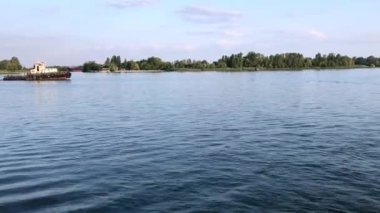 Yavaş yavaş nehir boyunca kargo taşıyan bir çekme gemisinin yan görünümü