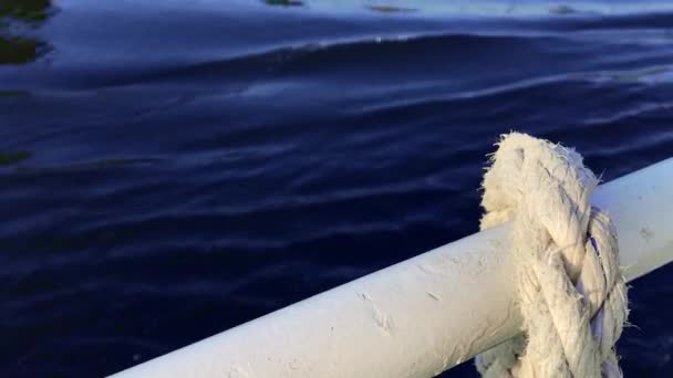 Close-up nautische knoop touw gebonden rond spel op boot of schip, boot aanmeren touw. Mariene touw op het schip. Het schip verlaat de haven. Vuurtoren. Aanmeren van touw. — Stockvideo