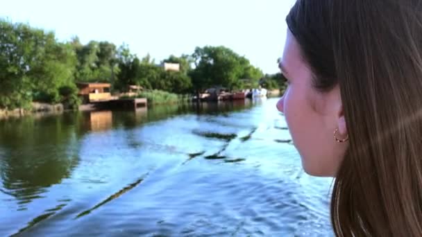 Retrato vista lateral jovem mulher caucasiana atraente fechando os olhos e virando o rosto para o sol apreciando os raios de sol e banhos de sol. Navegando em um barco de prazer no rio em um dia de verão — Vídeo de Stock