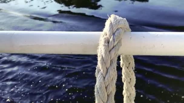 Close-up nautische knoop touw gebonden rond spel op boot of schip, boot aanmeren touw. Mariene touw op het schip. Het schip verlaat de haven. Vuurtoren. Aanmeren van touw. — Stockvideo