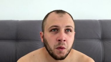 Güzel görünümlü, sakallı koyu saçlı adam eğlenceli komik yüzler sırıtıyor, grimaces yapar, dilini dışarı sopalarla, gözlerini haçlar, göz kırpıyor