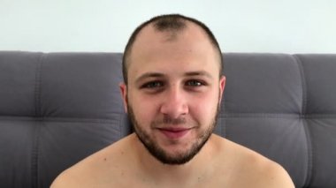 Güzel görünümlü, sakallı koyu saçlı adam eğlenceli komik yüzler sırıtıyor, grimaces yapar, dilini dışarı sopalarla, gözlerini haçlar, göz kırpıyor