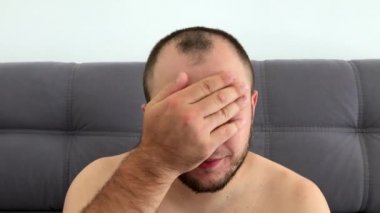 Güzel görünümlü, sakallı koyu saçlı adam eğlenceli komik yüzler sırıtıyor, grimaces yapar, dilini dışarı sopalarla, gözlerini haçlar, göz kırpıyor