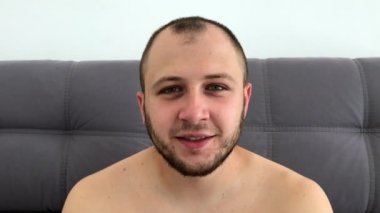 Güzel görünümlü, sakallı koyu saçlı adam eğlenceli komik yüzler sırıtıyor, grimaces yapar, dilini dışarı sopalarla, gözlerini haçlar, göz kırpıyor