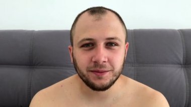 Güzel görünümlü, sakallı koyu saçlı adam eğlenceli komik yüzler sırıtıyor, grimaces yapar, dilini dışarı sopalarla, gözlerini haçlar, göz kırpıyor