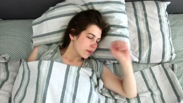 Hermosa joven morena encantadora duerme en su cama en las primeras horas de la mañana. Dulce y cálida vista de la niña durmiendo tranquilamente — Vídeos de Stock