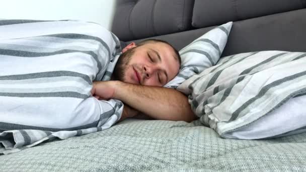 O homem está a dormir sozinho na cama debaixo do cobertor. Vista lateral . — Vídeo de Stock