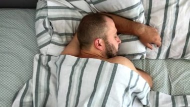 Genç adamın üst görünümü yatakta uyuyor.