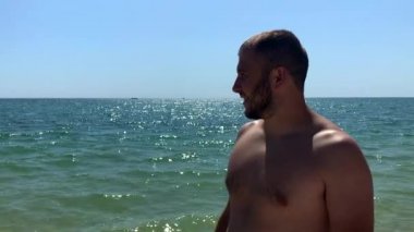 Beyaz adamın yan görünümü sahilde kalır. Başka bir yere bakıyor.