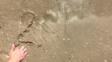 2019 yılı kuma çizilmiş sahilde bir dalga tarafından yıkanMış