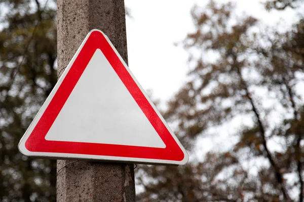 Empty red triangle road sign with not text and sign on the stree