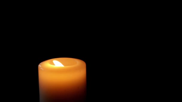 Duża świeca pali się w ciemności. Biała świeca. Czarne tło. zbliżenie — Wideo stockowe
