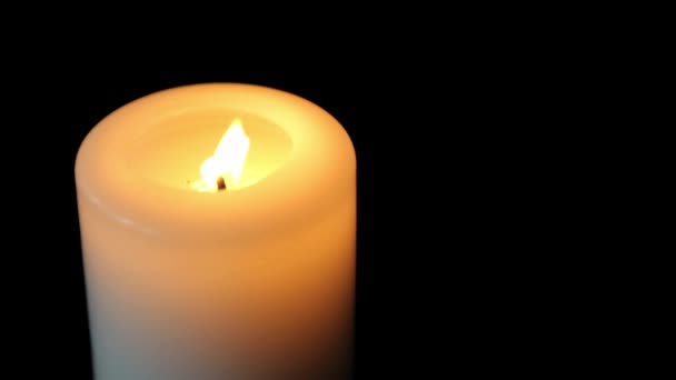 Im Dunkeln brennt eine große Kerze. weiße Kerze. schwarzer Hintergrund. Nahaufnahme — Stockvideo