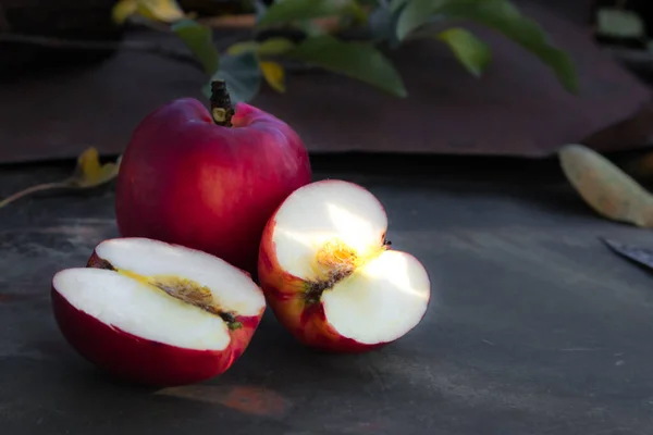 Gros plan d'une pomme rouge tranchée sur une table en bois — Photo