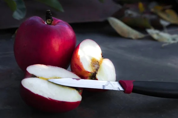 Gros plan d'une pomme rouge tranchée sur une table en bois — Photo