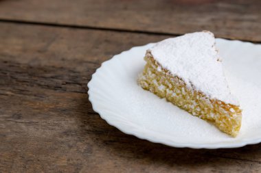 Kremalı ve beyaz çikolatalı kek. Beyaz tabakta dilimlenmiş kek. Tahta masada servis edilmiş. Kutlama etkinliği ya da doğum günü partisi için favori tatlı.