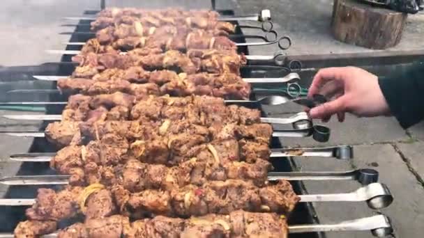 Mãos de um homem a rodar os espetos. Kebab Shish. Pedaços de carne de porco, frango ou cordeiro sendo fritos em uma grelha de carvão. Fritar pedaços de carne grelhados durante o resto. — Vídeo de Stock