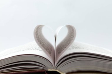Kalp sayfasıyla açılmış bir kitap. Defterdeki kağıtlarla yapılmış kalp şeklinin yakın çekimi