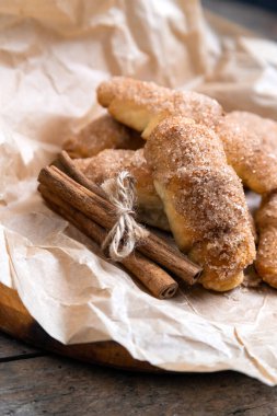 Tarçınlı taze kruvasanlar, ahşap arka plandaki kırışık kağıtta.