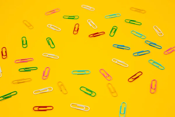Colorful paper clip on yellow background. Close up top view