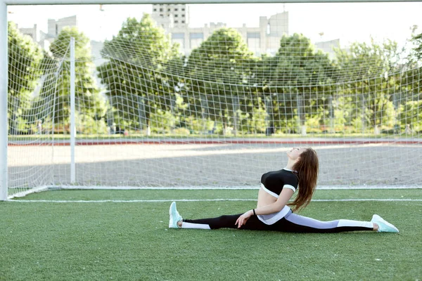 サッカー ゴール近くのひもの上に座ってスポーツ服の若い女性 — ストック写真