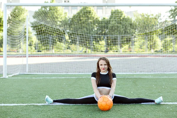 运动服上的年轻女子坐在绳子上 手里握着一个球 — 图库照片