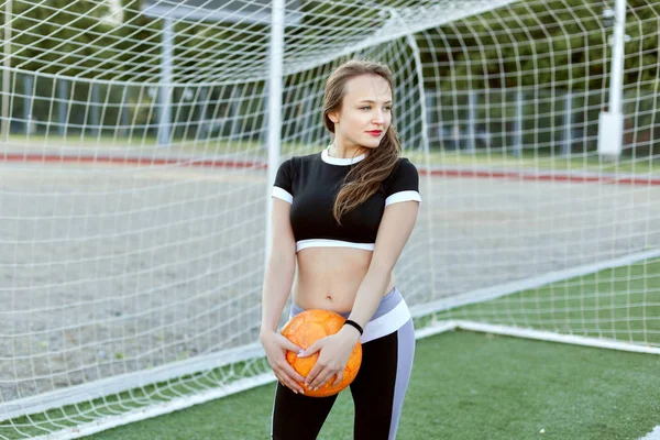 年轻女子站在足球球门附近 手捧着球 — 图库照片