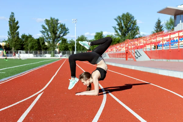 競技場でスポーツを行う若い女性 彼女は逆立ちを作る — ストック写真