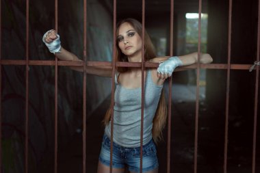 Genç kadın savaşçı bir demir çitin arkasında duruyor ve elleri Giydir.