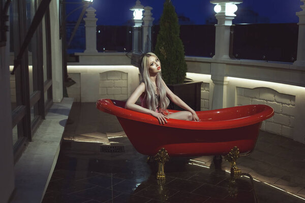 Woman in a luxurious red bath in the open air.