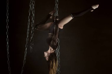 O performansı gösterir kadın jimnastikçi zincirleri üzerinde asılı.