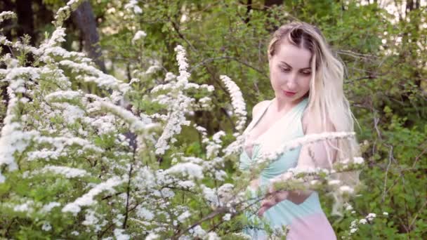 Νεαρή Γυναίκα Ξανθιά Ανάμεσα Ανθισμένα Δέντρα Στον Κήπο — Αρχείο Βίντεο