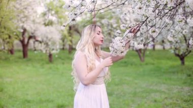 Çiçekli bahar bahçesinde, genç bir kadın çiçek kokusu sahiptir.