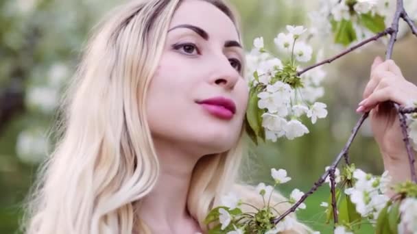 Κοντινό Πορτρέτο Μιας Ξανθιάς Κοπέλας Μυρίζει Ανθισμένα Δέντρα Την Άνοιξη — Αρχείο Βίντεο