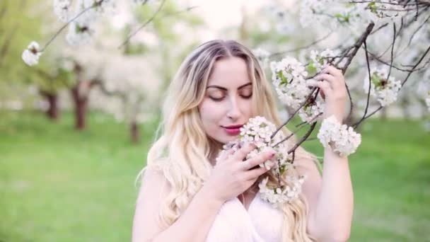 一个年轻的女孩在花园里拥抱春天的开花树 — 图库视频影像