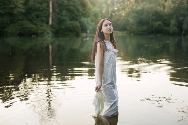 Junge Frau im Nachthemd steht im Fluss. — Stockfoto