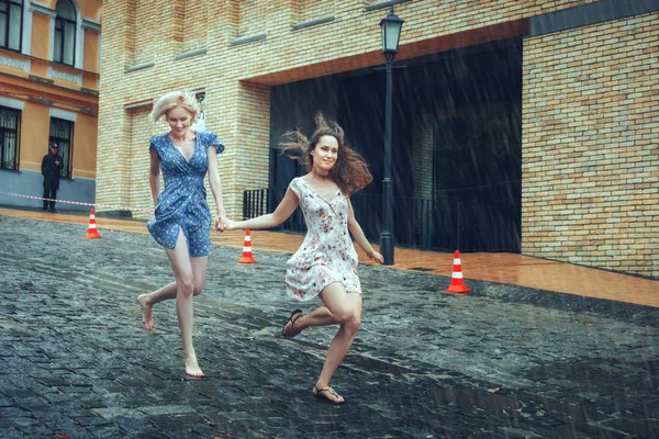Duas mulheres correm à chuva na estrada . — Fotografia de Stock