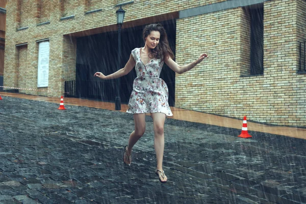 La mujer corre en la carretera bajo la lluvia de verano . — Foto de Stock