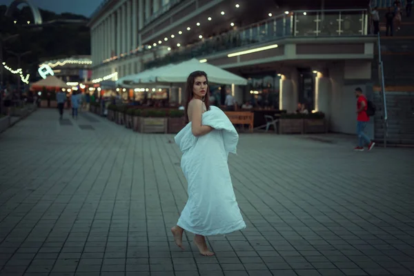 Молодая женщина ходит по городу в белом одеяле . — стоковое фото