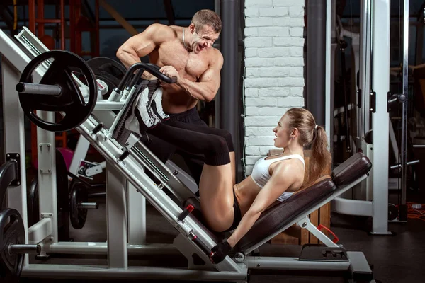 Man trainer aiuta una donna a eseguire esercizi . — Foto Stock