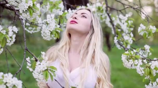 美丽的年轻女子站在花园里一棵开花的树旁边 — 图库视频影像