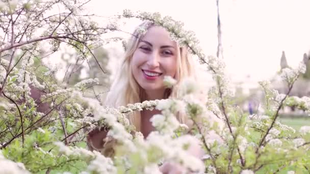 年轻美丽的女人从开花的灌木丛后面窥视而笑 — 图库视频影像